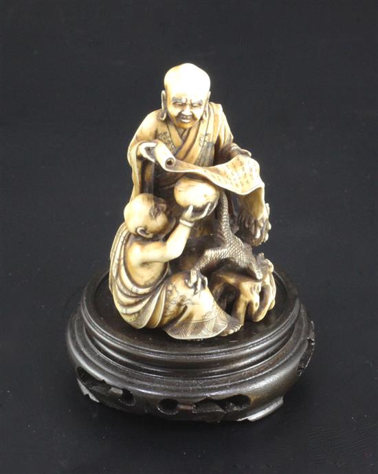 A Japanese ivory okimono netsuke of Handaka Sonja invoking a dragon with another rakan, Meiji period, height 6cm, wood stand